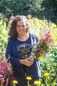 Deb Habib standing in a field of tall grass, holding a bouquet of fresh cut flowers